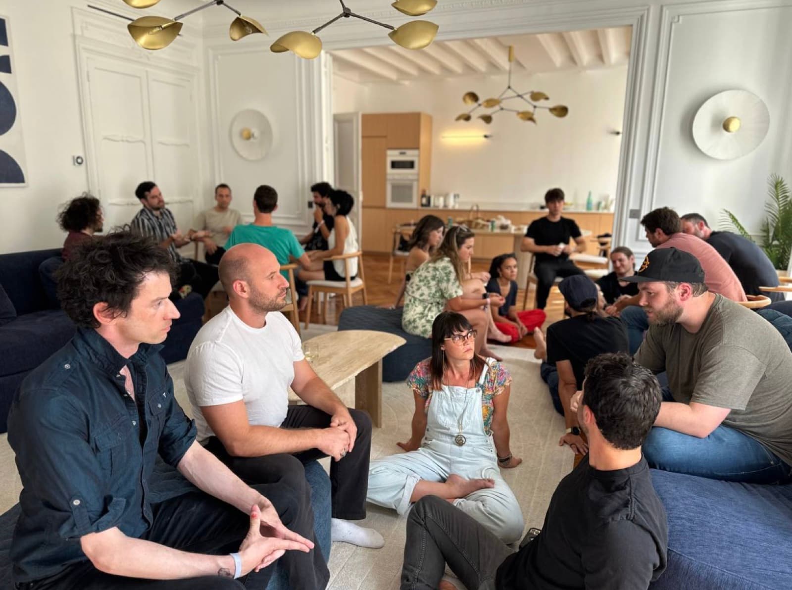 Small groups in conversation on the floor and sofas of the apartment.
